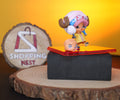 TONY CHOPPER FIGURE LEFT SIDE on a reflective surface with a 'Shopping Nest' sign in the background.