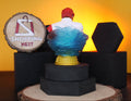 Figurine of a LUFFY AND SHANKS with red hair BACK SIDE on a stand with a 'Shopping Nest' sign in the background.