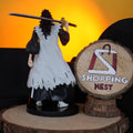 BLEACH KENPACHI Figurine of a character holding a sword on a wooden stand with 'Shopping Nest' logo in the background.