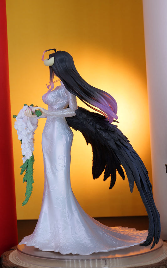 Figurine of a character in a white dress with black wings against a yellow background