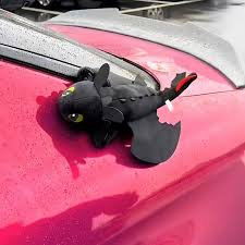 Car air freshener with a dragon design attached to a car's sunroof.